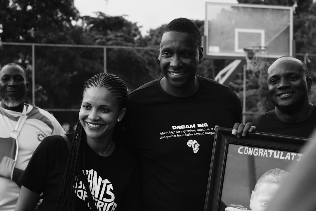 A diverse group of basketball players and volunteers organizing a community tournament, with registration tables, basketball courts in the background, and fundraising banners displaying donation goals